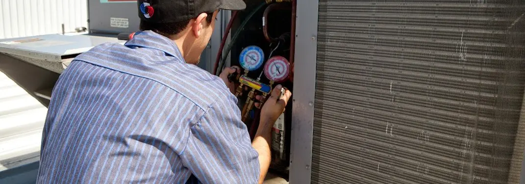 HVAC technician servicing a condenser unit in Ambler